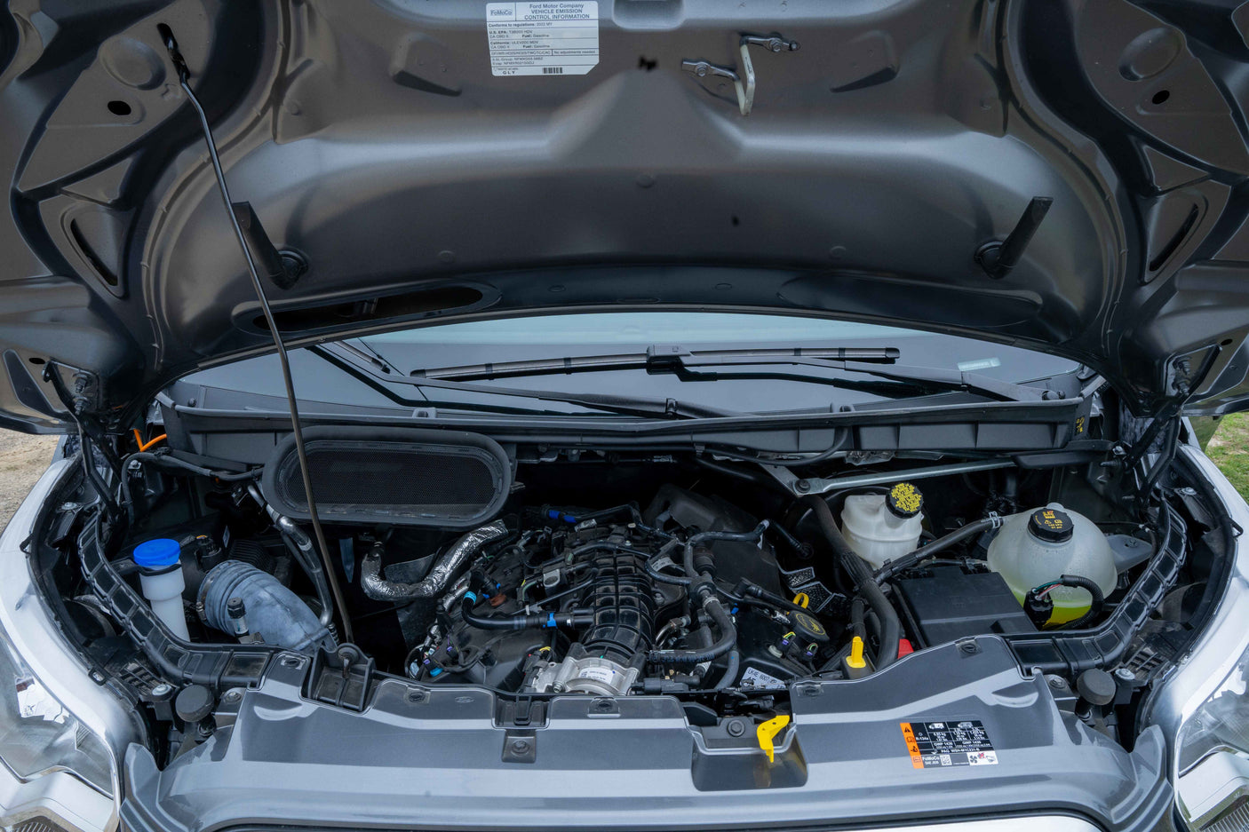 Open hood of a 2022 Ford van, suitable for an RV rental, showing the engine and fluid reservoirs.