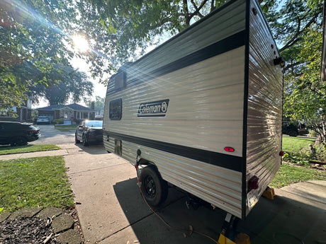  ready for your next RV rental adventure. Parked on a sunny driveway with trees overhead.|Rear view of a white RV