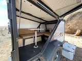 Compact Tiger Moth RV rental interior featuring a dinette converting to a bed, ideal for outdoor adventures.