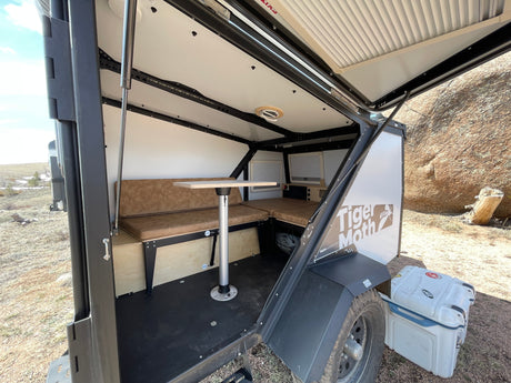 Compact Tiger Moth RV rental interior featuring a dinette converting to a bed, ideal for outdoor adventures.
