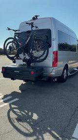 Silver RV rental equipped with two bikes on a rear rack and a Yakima cargo box, perfect for road trips & outdoor adventures.