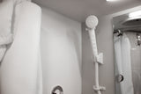 Clean shower amenities in an RV rental. Handheld showerhead, mirror, and white towel/robe offer comfort.