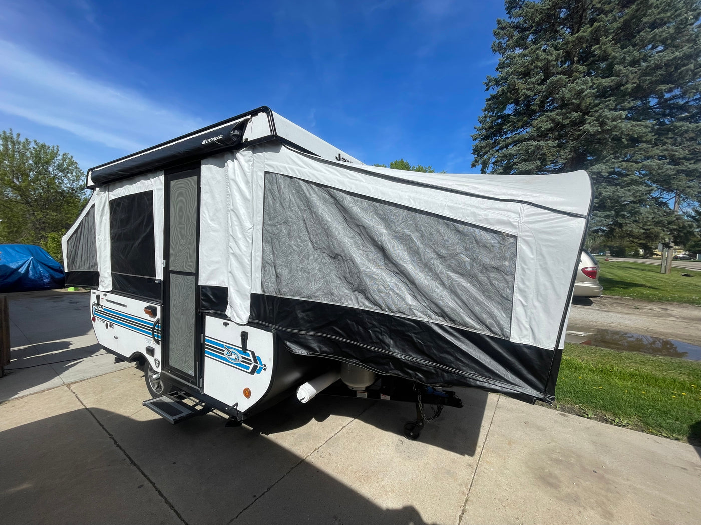This white and black pop-up camper, a great RV rental option, is set up on a sunny driveway. — photo 2