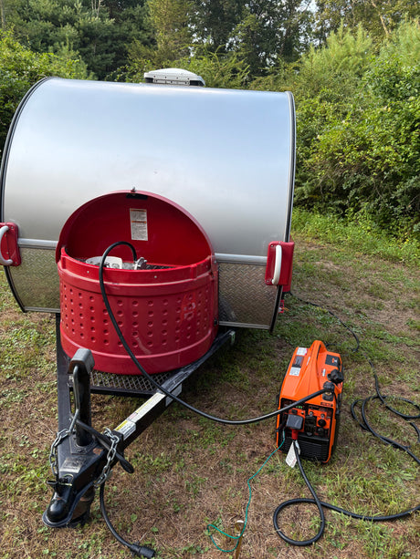 An RV rental teardrop trailer, with a propane tank, connects to a portable generator for off-grid power.