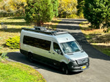 Silver Airstream Mercedes Sprinter camper van, perfect for an RV rental road trip, parked on a driveway.