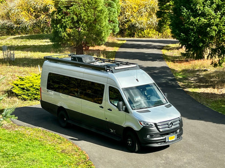 Silver Airstream Mercedes Sprinter camper van, perfect for an RV rental road trip, parked on a driveway.
