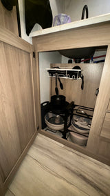 Efficient under-sink storage in an RV rental kitchen, showing organized pots, pans, and utensils.