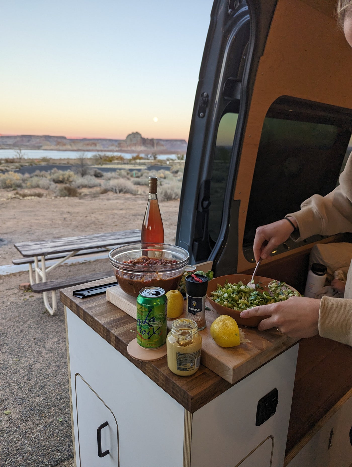 Outdoor cooking from an RV rental, preparing chopped greens and chili at sunset by a desert lake. — photo 10
