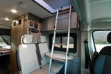 RV rental interior showing a dinette, ladder to a bunk, and control panels for a comfortable mobile living space.