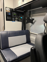 RV rental tech: main control panel, entertainment mount, and plush seating in a camper van interior.