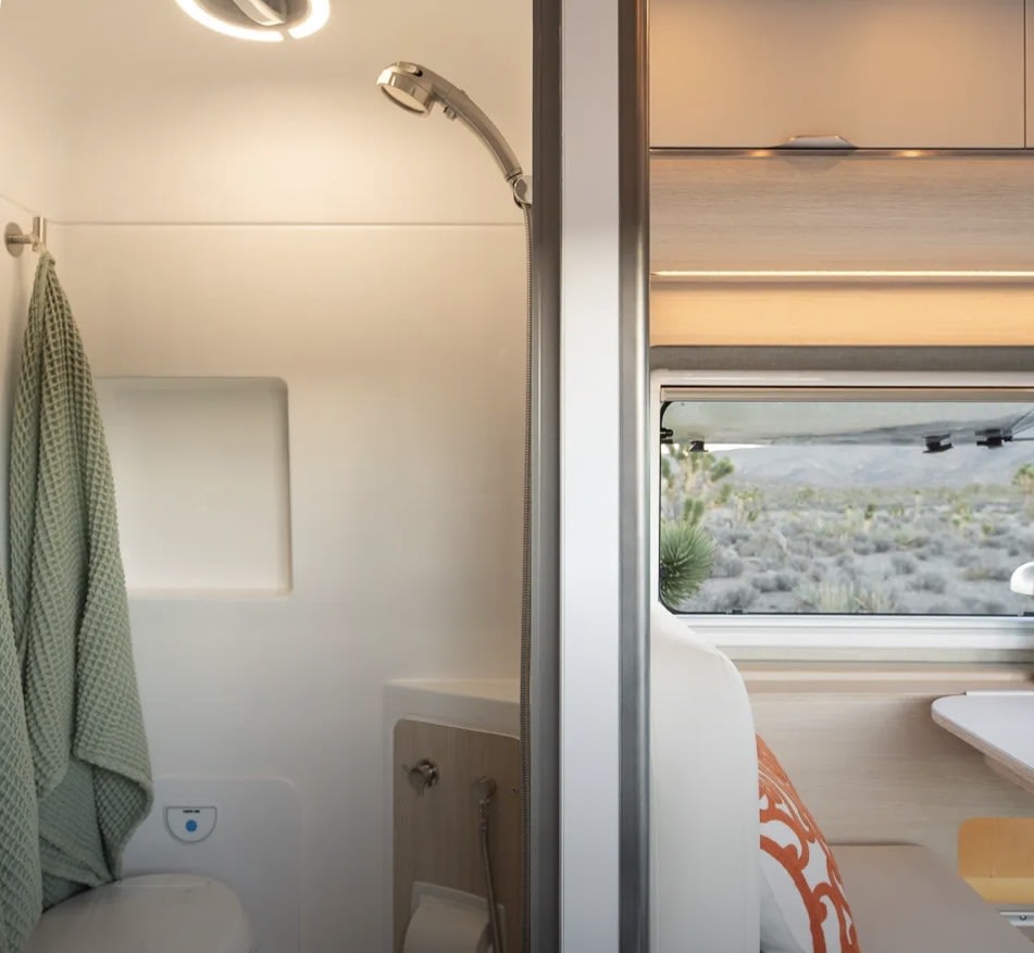 RV rental interior: A compact shower and toilet area on the left, with a window offering desert views on the right. Modern camper amenities. — photo 3