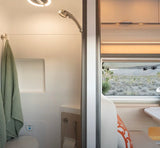 RV rental interior: A compact shower and toilet area on the left, with a window offering desert views on the right. Modern camper amenities.
