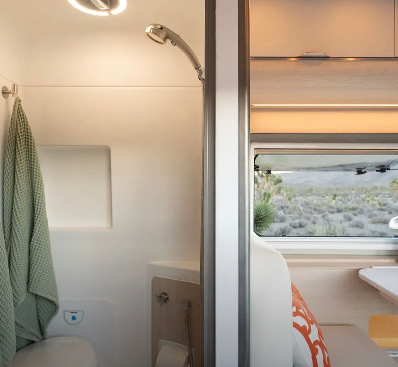 RV rental interior: A compact shower and toilet area on the left, with a window offering desert views on the right. Modern camper amenities. — photo 3