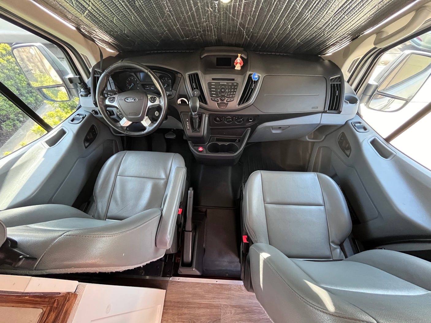 Inside an rv rental: View of the front cabin with gray seats, dashboard, and steering wheel, ready for travel.