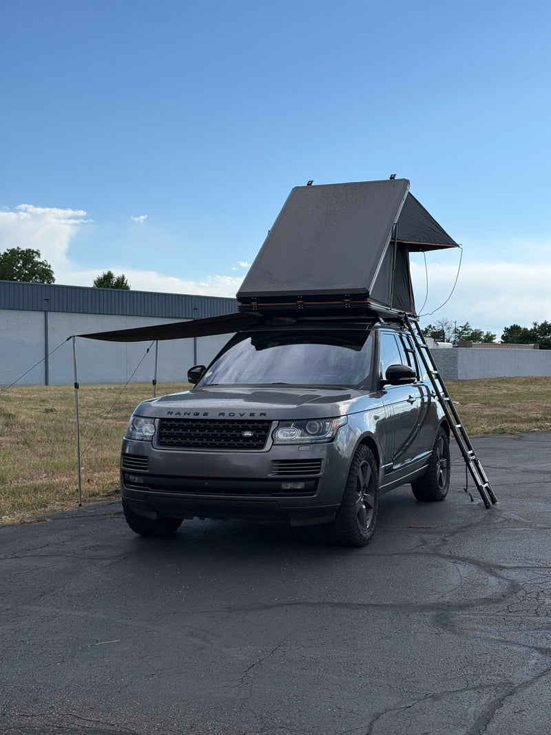 Dark grey Range Rover SUV with an open rooftop tent, ladder, and extended awning, perfect for an adventurous RV rental. — photo 8