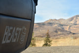 "BEAST" rv rental, prominent logo on dark surface, with blurred mountains & trees in scenic outdoor backdrop.
