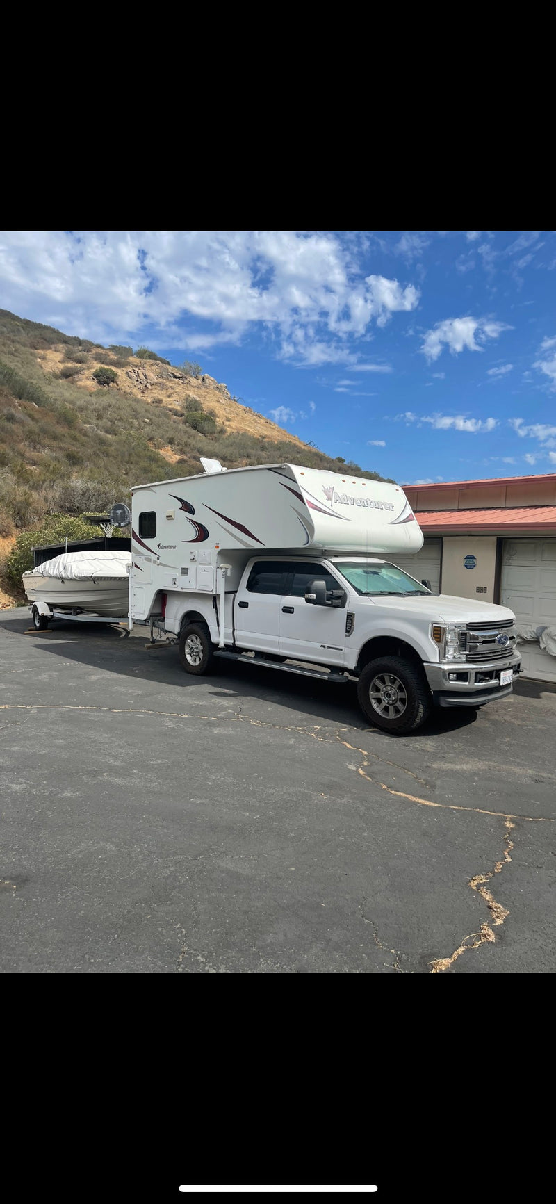 This versatile white truck camper RV rental, towing a boat, is parked on a sunny day, ready for your next getaway. — photo 14