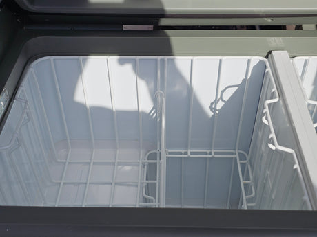Inside an empty RV rental portable fridge/freezer with dual compartments and wire baskets, ready for your camping or road trip.