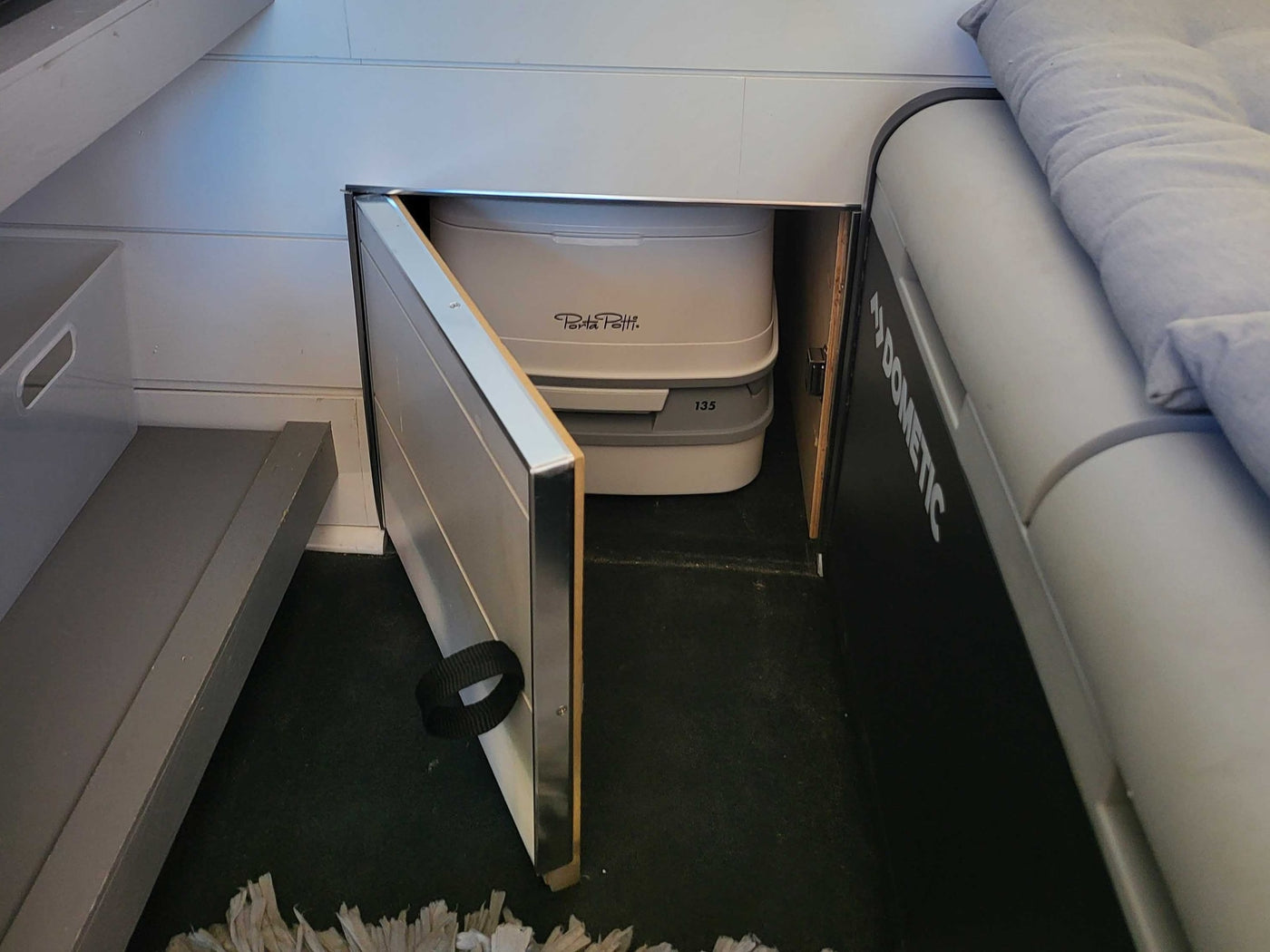 An RV rental's clever storage reveals a Porta Potti portable toilet. Dometic cooler and sleeping area nearby. — photo 7