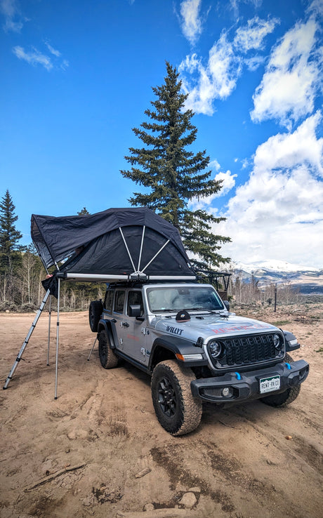Adventure-ready RV rental Jeep with rooftop tent, parked in a scenic mountain landscape.