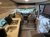 Inside a well-equipped RV rental: modern kitchen with sink & stove, dual cockpit seats, and snowy views outside. Great for travel.