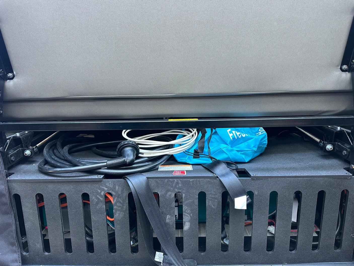 RV rental: Under-seat compartment for power cables, a bag, and RV electrical system components.