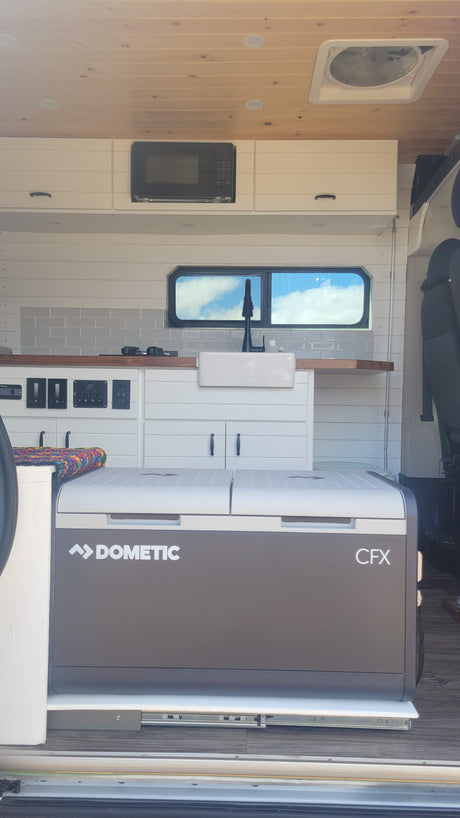 Modern rv rental camper van kitchen with sink, microwave, and pull-out Dometic CFX cooler.
