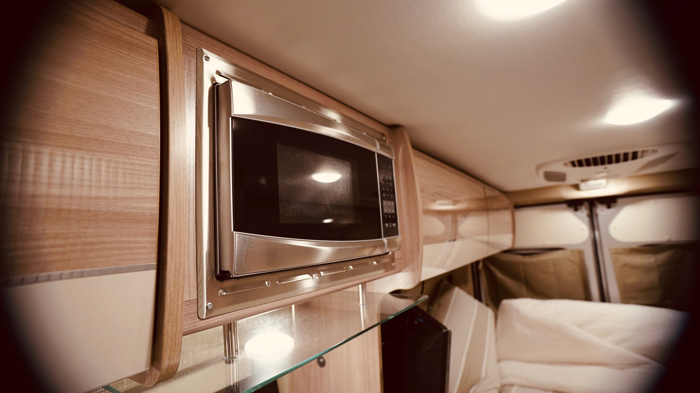 Explore this RV rental's modern interior: a stainless steel built-in microwave, wooden cabinetry, and bright, comfortable living space.