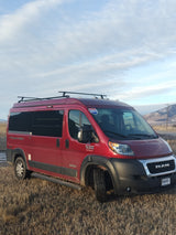Explore landscapes with this red Pleasure-Way Tofino camper van, an ideal rv rental, parked in a dry field with mountains.
