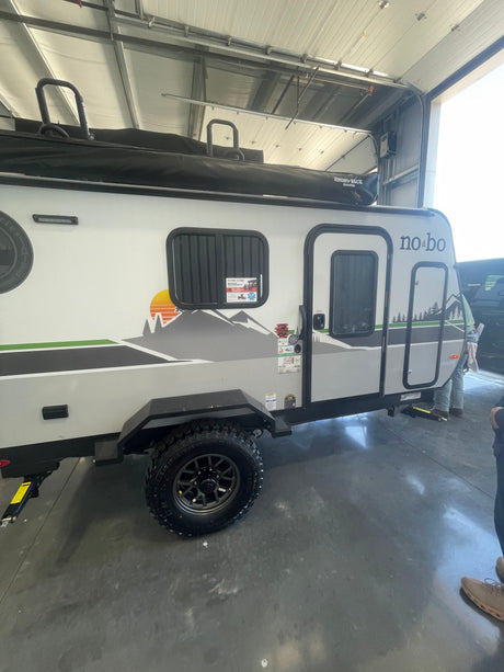 Compact no-bo travel trailer, equipped with off-road tires and Rhino-Rack awning, ready for your next RV rental adventure.