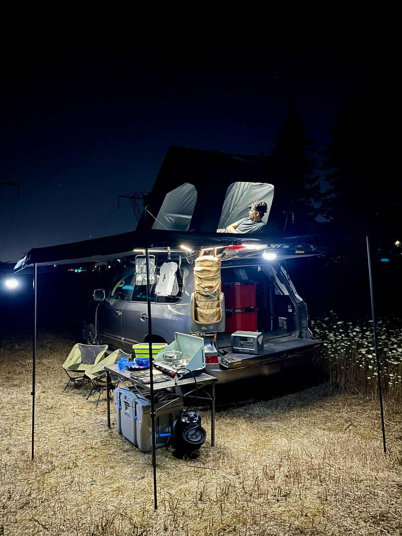 Night car camping setup: An SUV with a rooftop tent and awning provides an RV rental-like experience. Illuminated outdoor kitchen & relaxing space. — photo 10