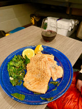 Cozy RV rental dinner: perfectly cooked salmon with spinach and lemon, paired with red wine. Simple, tasty travel meal!