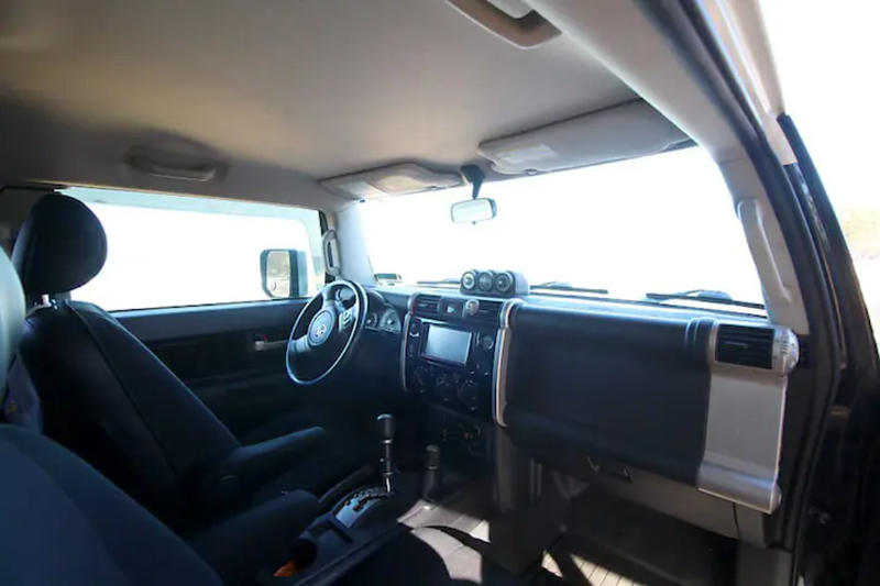 Bright interior of an SUV showing the steering wheel, dashboard with adventure gauges, and front seats, ideal for an RV rental. — photo 4