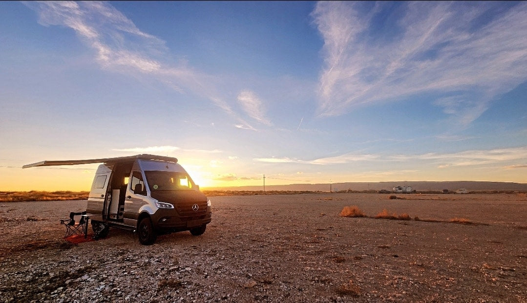  surrounded by rocks and trees. Adventure awaits.|An RV rental camper van parked in a wide-open desert — photo 2