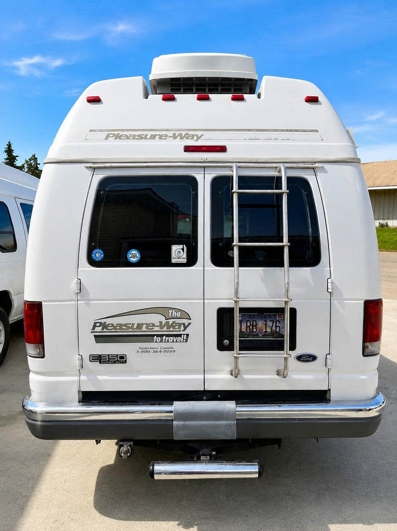  with an awning extended over two chairs on a driveway next to a house.|White camper van (rv rental) with extended awning — photo 6
