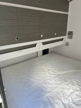 RV rental bedroom: white bed, gray overhead cabinets with lights, and useful labels for guidebooks and storage.