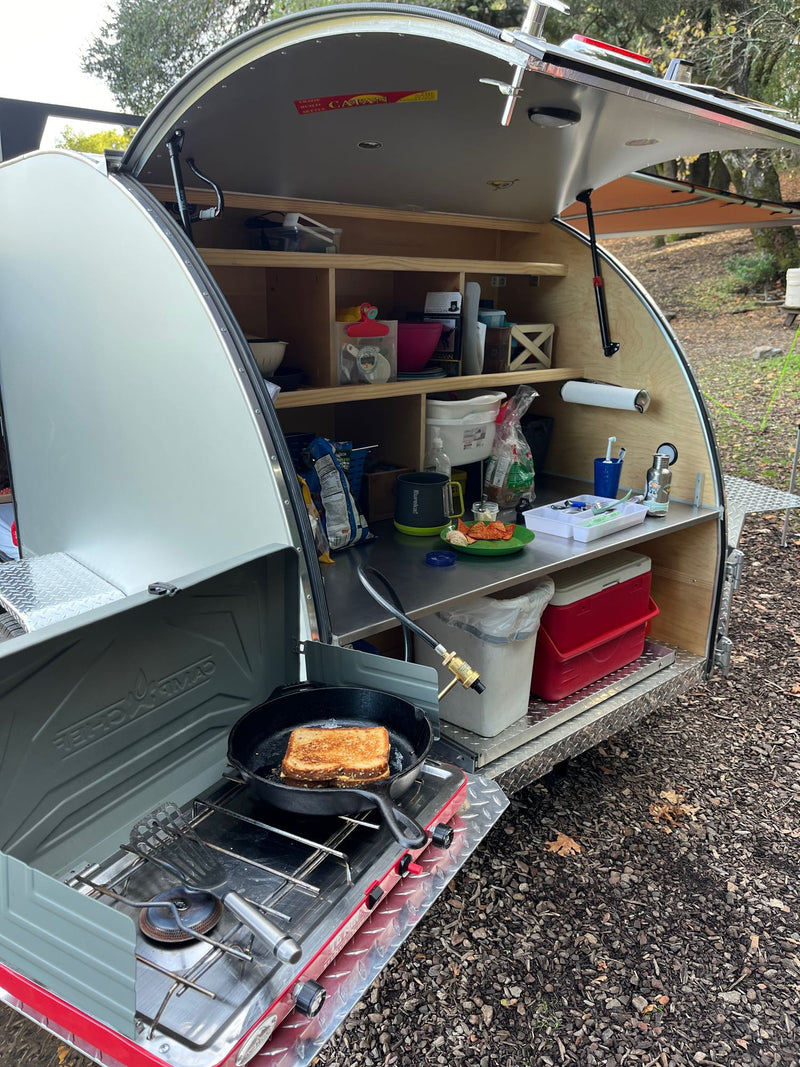  and storage box in a woodsy setting.|Cozy RV rental camper interior with a bed — photo 18