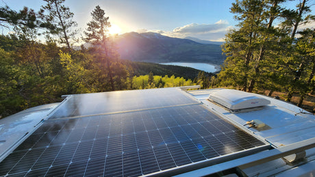 RV rental with rooftop solar panels, offering stunning views of a mountain lake at sunset, perfect for off-grid travel.