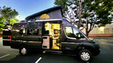 Ready for adventure! This dark grey camper van, pop-top open & interior lit, highlights an ideal rv rental for travel.