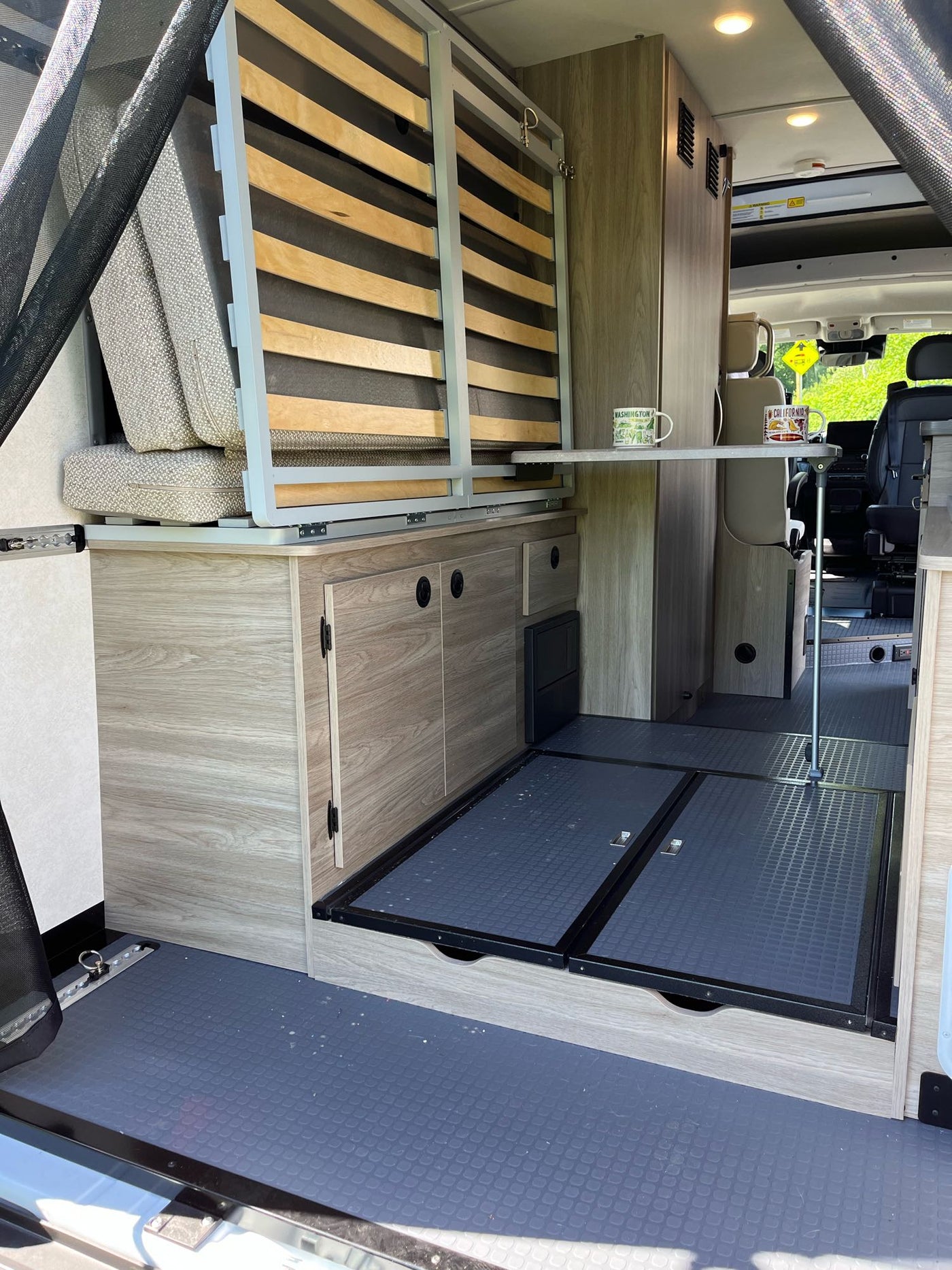  and a ladder to a comfortable upper bed.|RV rental's compact kitchen setup: a Suburban gas stove with a pan and spatula — photo 11