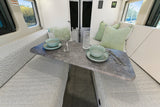 This RV rental offers a comfortable dinette setup with chevron patterned cushions and a stone-look table, ready for dining.