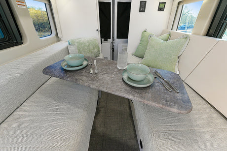 This RV rental offers a comfortable dinette setup with chevron patterned cushions and a stone-look table, ready for dining.