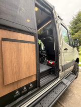Winnebago Revel RV rental with an open side door, showcasing its modern interior, steps, and utility controls for a camper van.