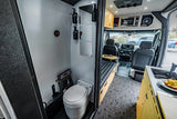 RV rental interior featuring a compact wet bath with toilet and shower, kitchen with sink, and a convertible sleeping area.