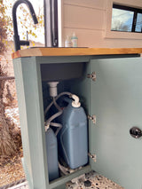 This RV rental features a compact interior sink with a practical water system, including fresh and grey water tanks inside the cabinet.