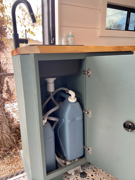 This RV rental features a compact interior sink with a practical water system, including fresh and grey water tanks inside the cabinet.