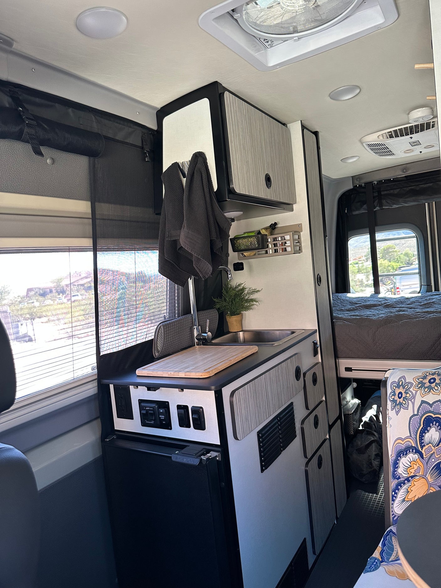Modern RV rental: compact camper van interior with kitchen (sink, fridge, cabinets), bed, & storage. Optimized for small space living.