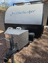 Front view of a Bushwhacker off-road teardrop trailer for rv rental, showing solar panels, front storage box, and gravel ground.