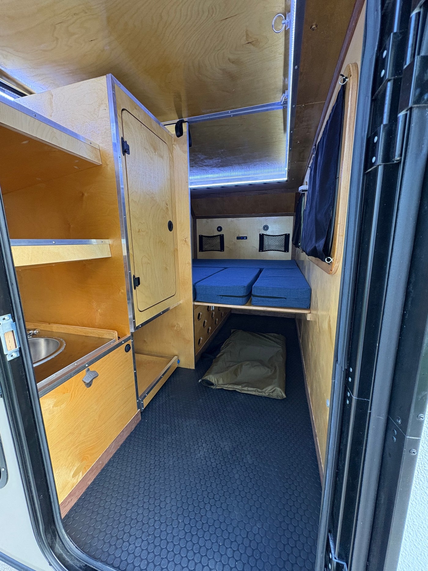 Cozy rv rental interior: light wood, blue sleeping cushions, compact sink, and storage for adventurous trips. — photo 3
