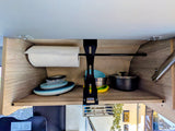 Organized RV rental kitchen cabinet with paper towels, stacked plates, bowls, and cooking pots for efficient travel.